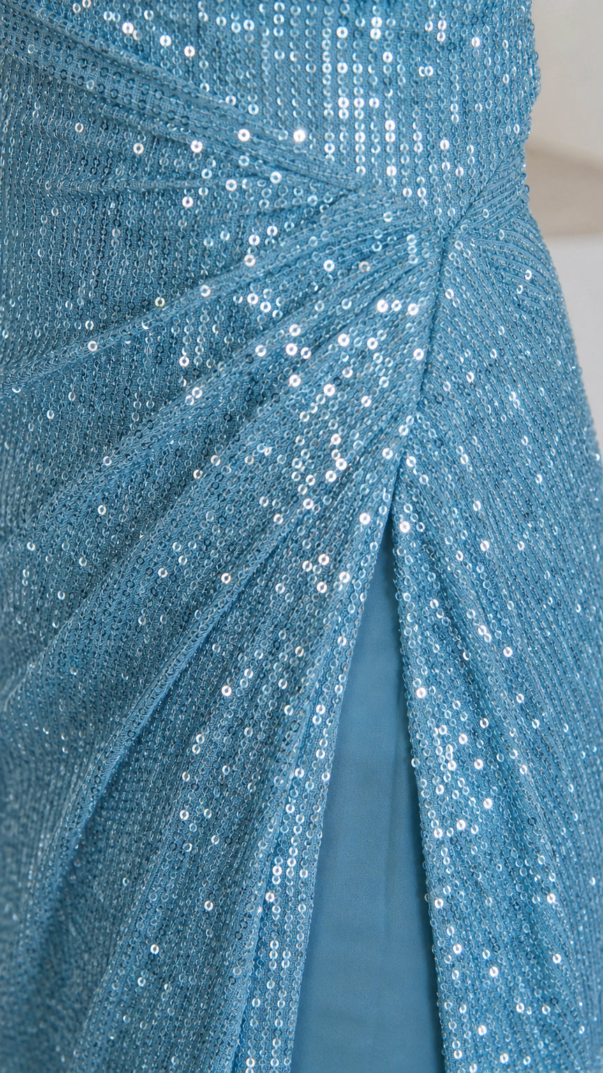 Close-up of ice blue sequin fabric, ruching, and inner lining at the slit