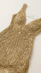 Close-up detail of intricate beadwork and fringe on the gold dress