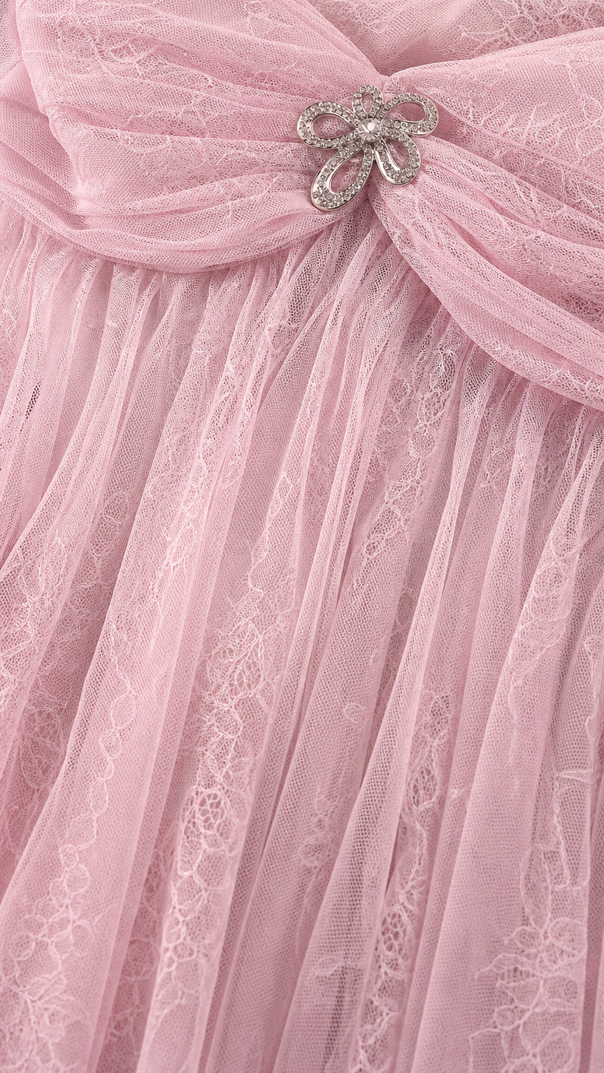 Close-up of pink tulle fabric and crystal bow brooch detail