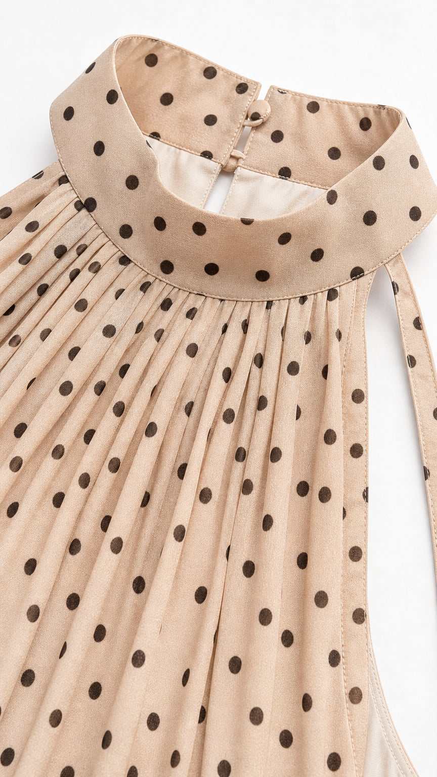 Close-up of high halter neckline and polka dot pattern on beige fabric