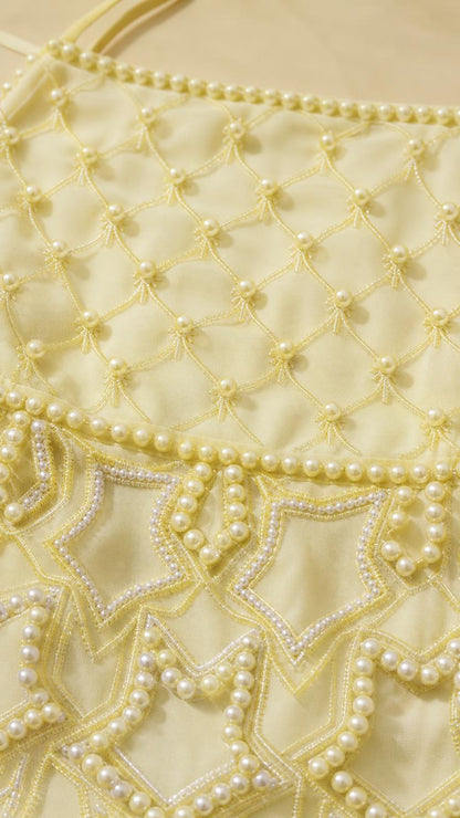 Close-up detail of geometric pearl beadwork on yellow dress