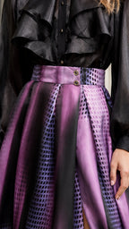 Close up of black ruffle blouse and patterned high waist skirt