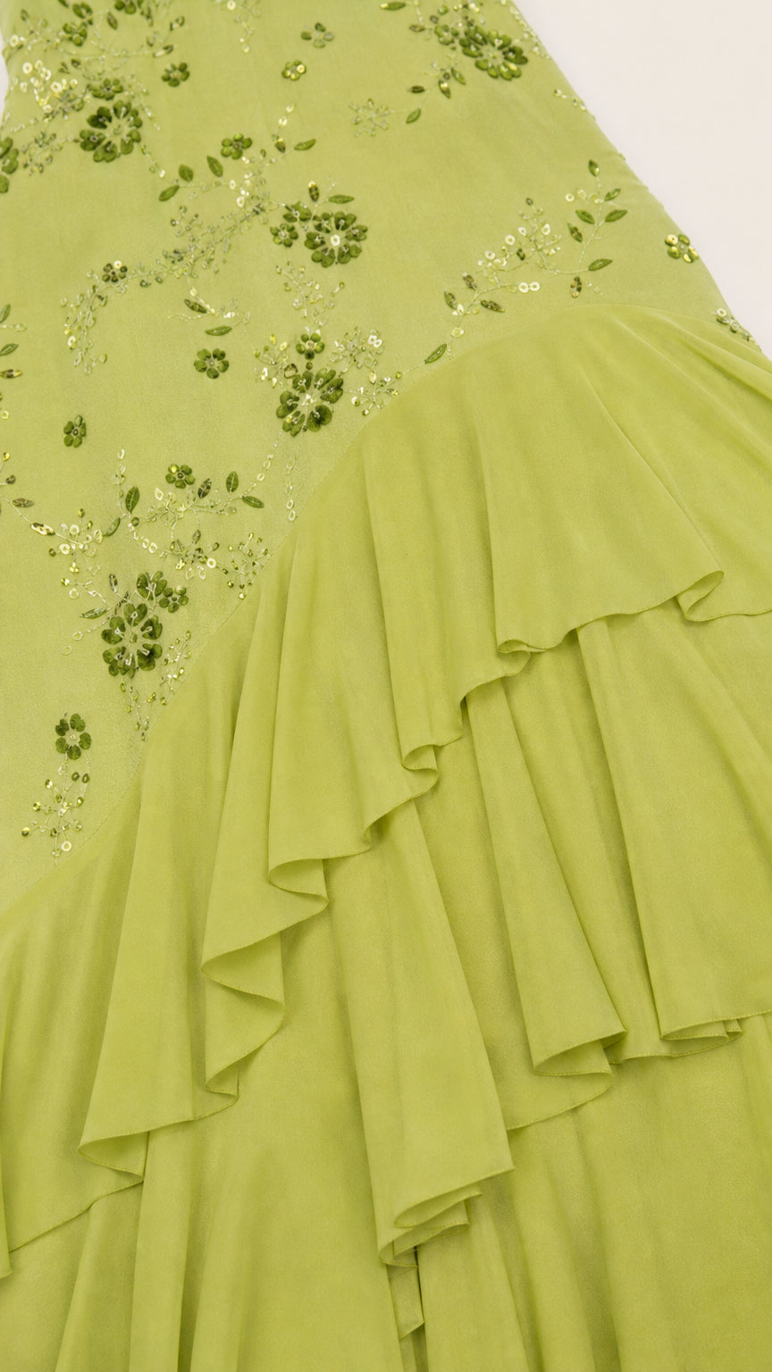Close-up of floral beadwork and tiered ruffles on olive green fabric