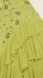 Close-up of floral beadwork and tiered ruffles on olive green fabric