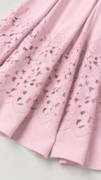 Close-up of intricate cutwork embroidery hem on pink dress