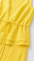 Close-up detail of the drawstring waist and layered top on yellow dress