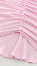 Close-up detail of ruching and hemline on pink dress