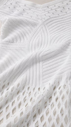 Close-up of white knit fabric texture and embellished bodice details