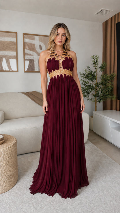 Model wearing burgundy gold-trimmed halter pleated maxi dress