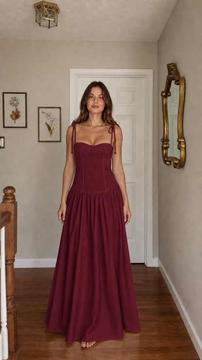 Front view of woman wearing burgundy tie-strap corset maxi dress